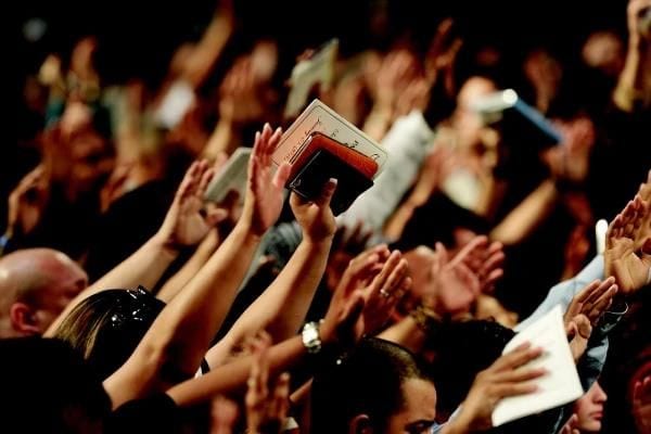 Des mains levées tenant des Bibles
